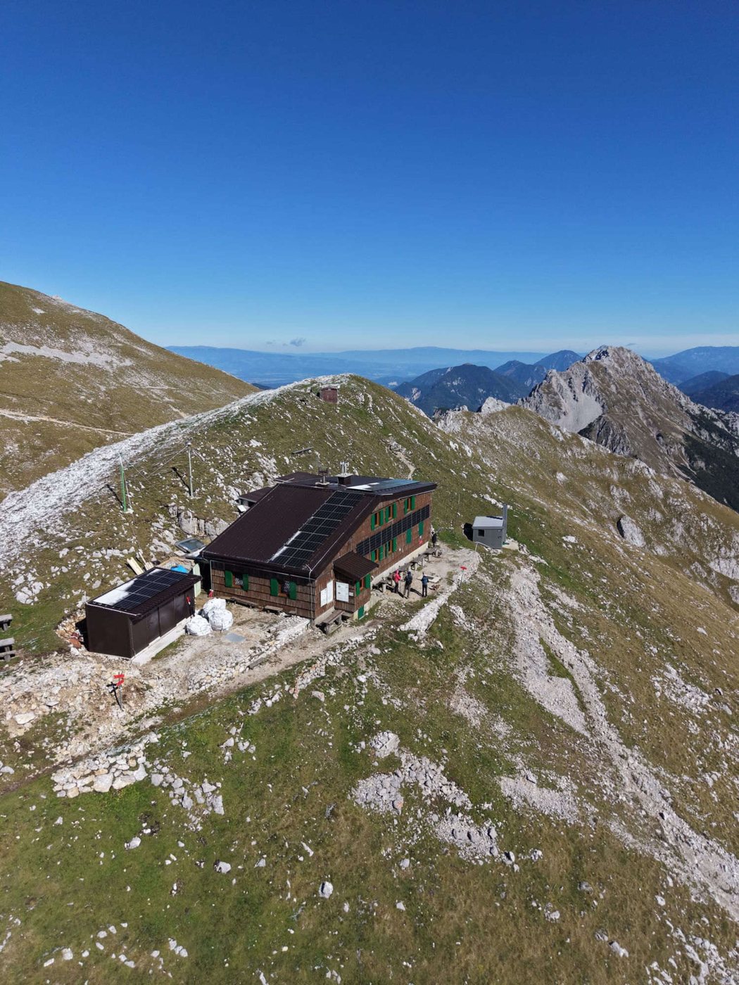 Prešernova koča na Stolu s paneli na strehi in fasadi — pogled iz zraka